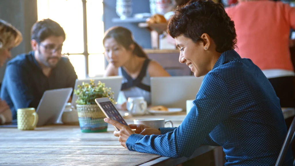 Busy coworkers in a cafeteria using laptops and devices, enjoying seamless internet access managed by Monyfi Wi-Fi management system