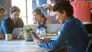 Busy coworkers in a cafeteria using laptops and devices, enjoying seamless internet access managed by Monyfi Wi-Fi management system
