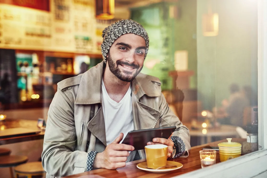 Man using guest Wi-Fi on a tablet in a café, representing how GDPR affects customer Wi-Fi usage in businesses
