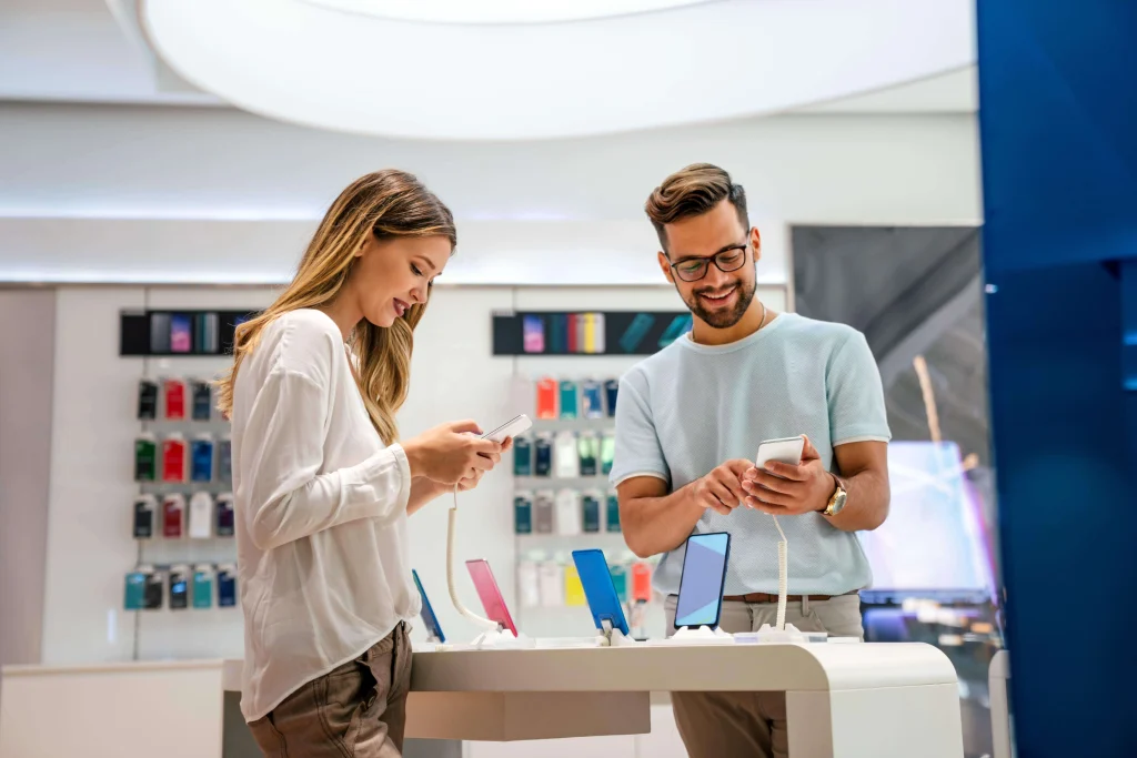 Two customers testing smartphones in a retail store connected to Wi-Fi.