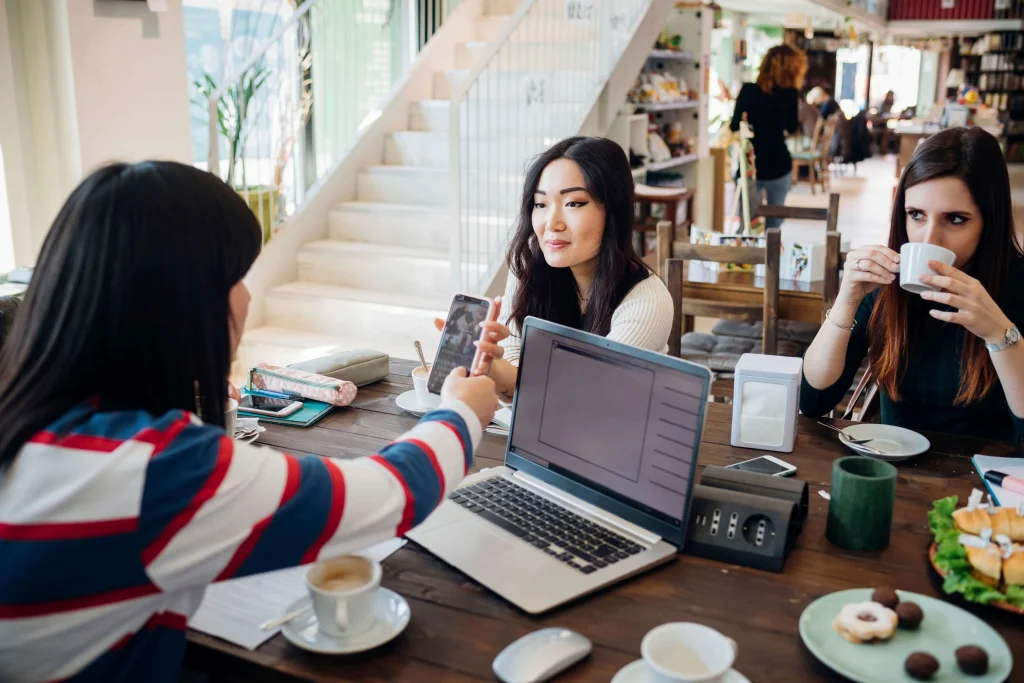 A group of women working on laptops and sharing ideas over coffee in a café with Wi-Fi.