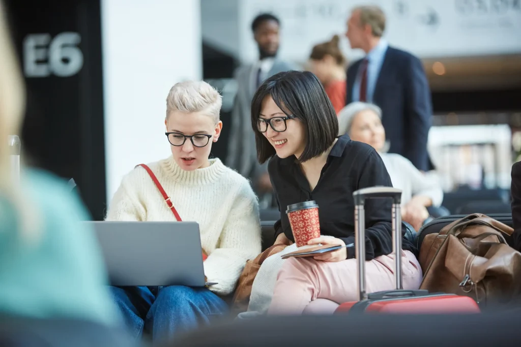 Two travelers using a laptop at an airport while connected to guest Wi-Fi, illustrating how CCPA applies to public Wi-Fi networks