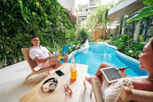Couple using laptops by a hotel swimming pool while connected to guest Wi-Fi