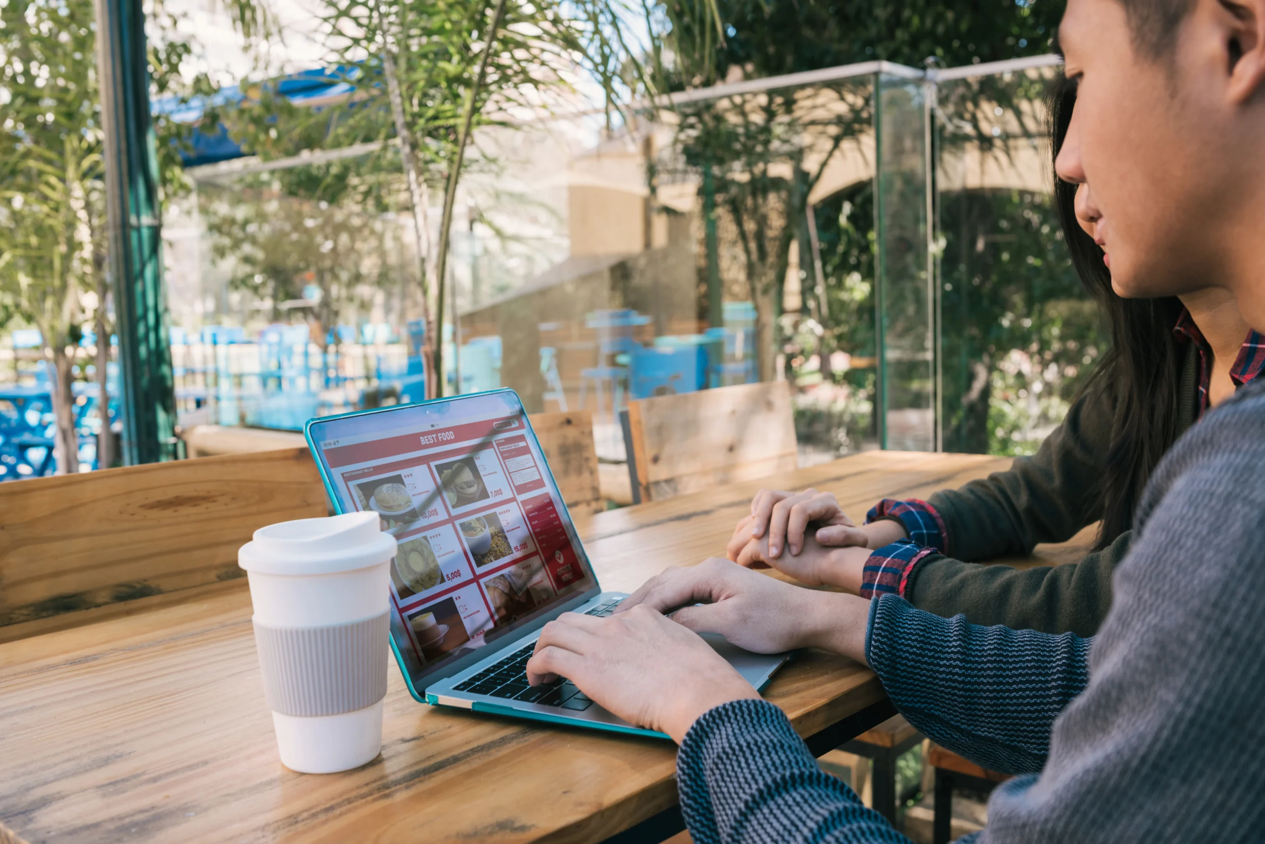 Customers using a laptop on guest Wi-Fi while browsing food options in a cafe