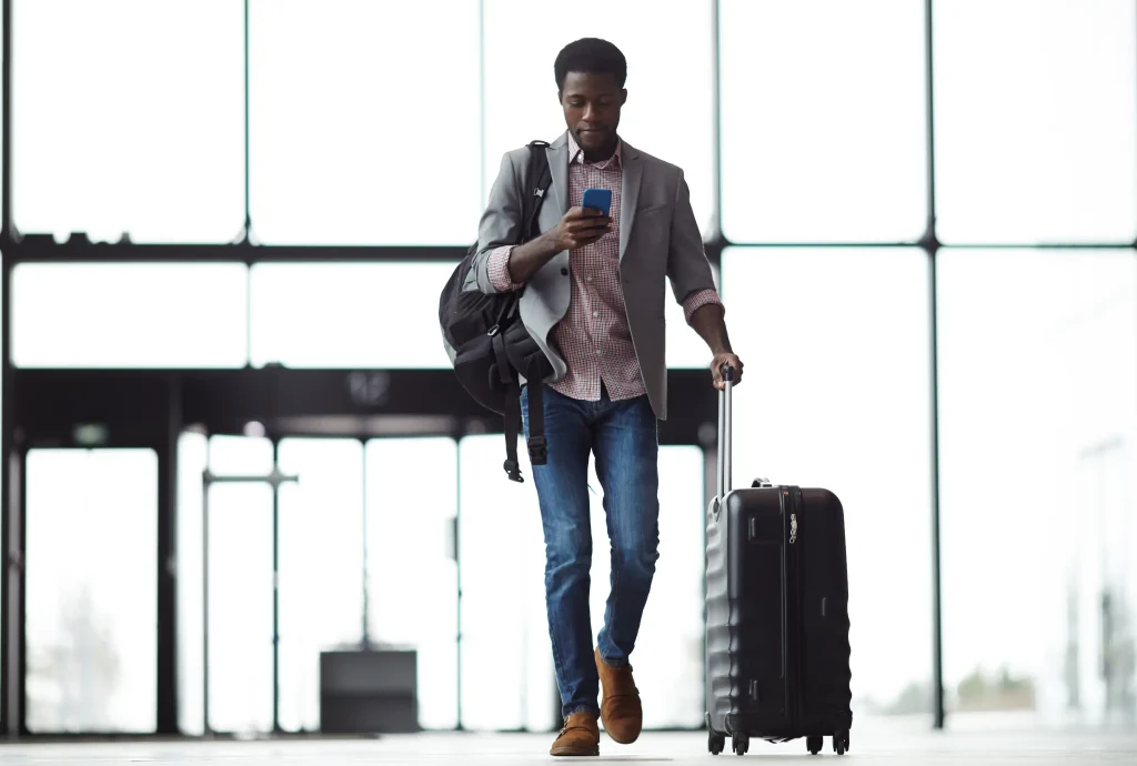 Traveler accessing public guest Wi-Fi of an airport on a smartphone while moving through a terminal