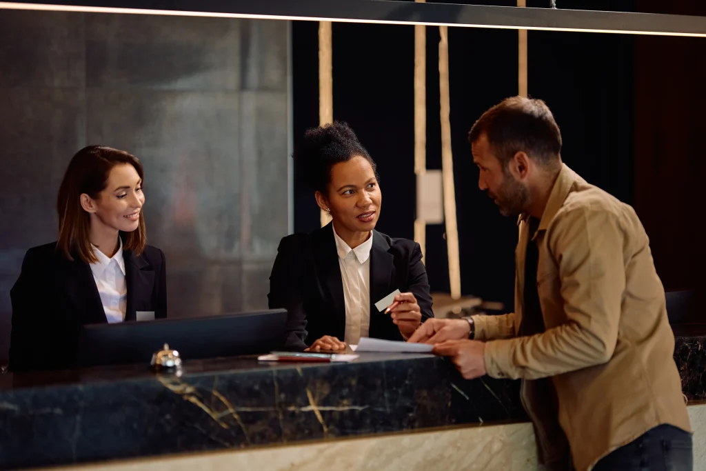 Hotel manager assisting guest with Wi-Fi login and digital services at reception desk