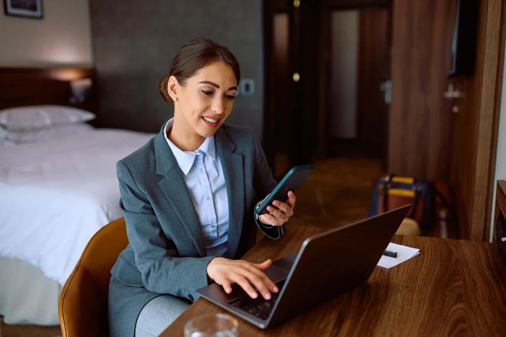 Business traveler using laptop and smartphone in hotel room with high-speed Wi-Fi connection