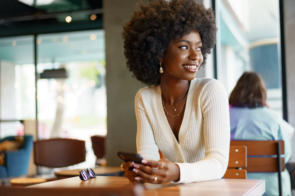 Young woman using a mobile phone at a coffee shop with guest WiFi access